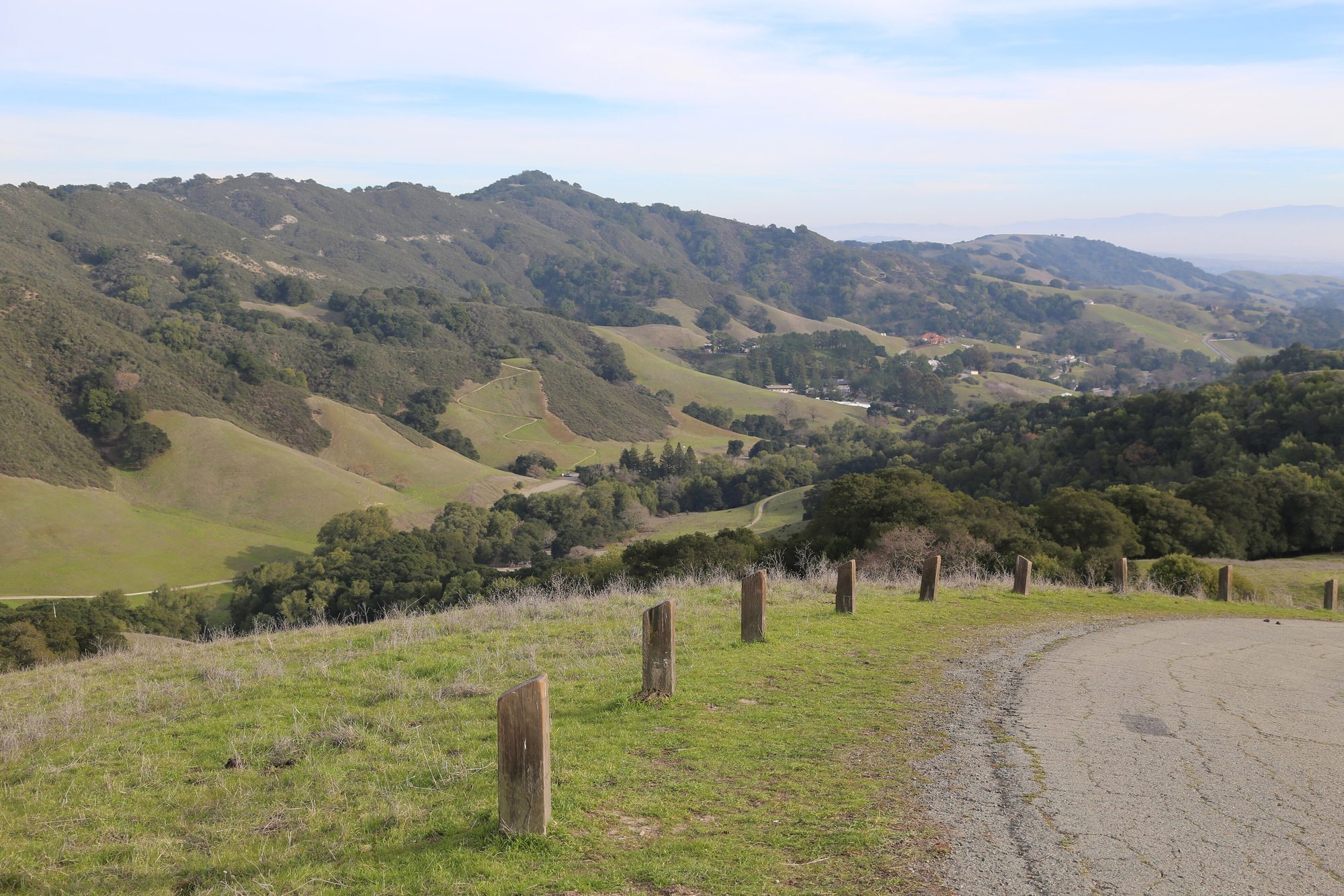 Green rolling hills dotted with oaks, with a trail curving through the Bollinger Creek valley.